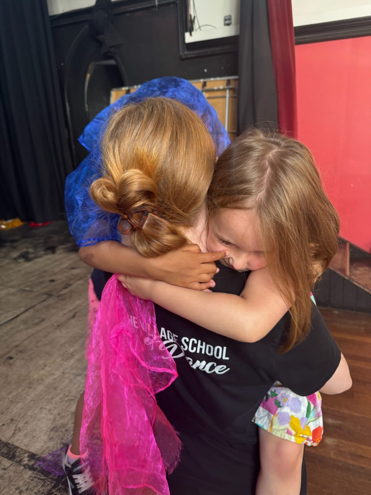 Two young dancers sharing a hug at The Village School of Dance in Wimbledon